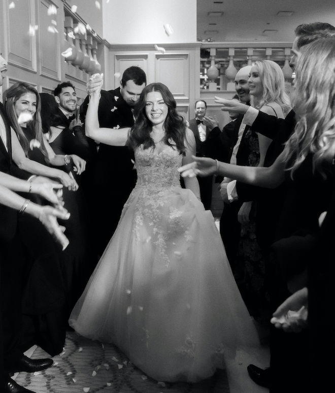 The bride and groom celebrating and exiting their wedding reception surrounded by their guests. 