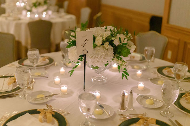 Green, gold and white decor detail the wedding reception tables in the hotel ballroom. 