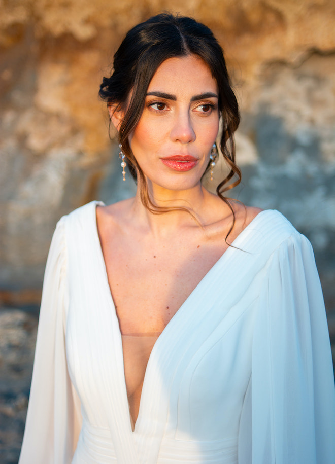 The bride wearing a long sleeve Justin Alexander gown, pearl earrings and an updo hairstyle. 