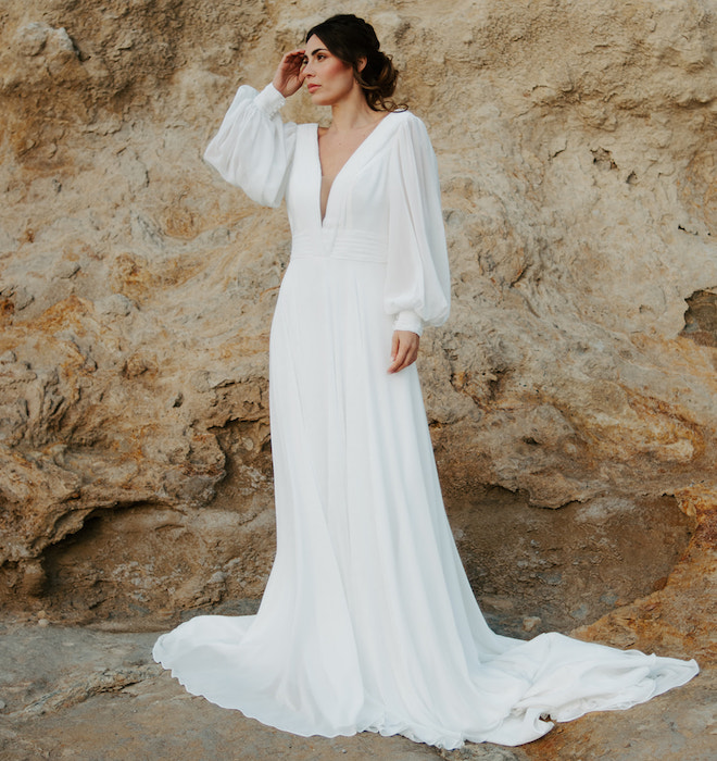 The bride wearing a long-sleeve wedding gown with her hair in a low bun. 