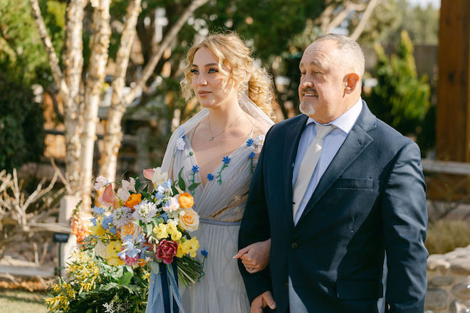 The bride holding a bouquet and walking down the aisle with her father.