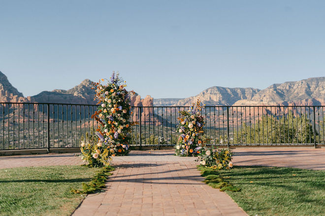 Floral installations with greenery, citrus and blue blooms serving as the altar overlooking the mountains. 