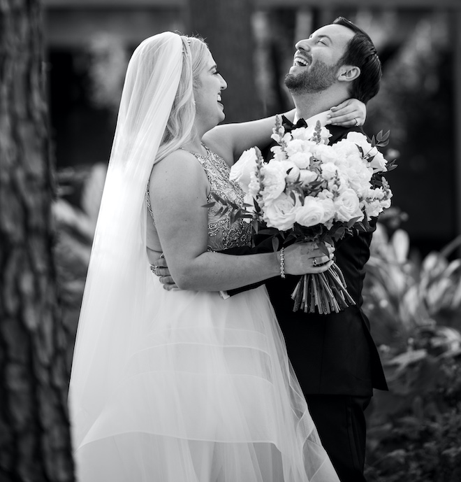 The bride and groom laughing while hugging after their first look.