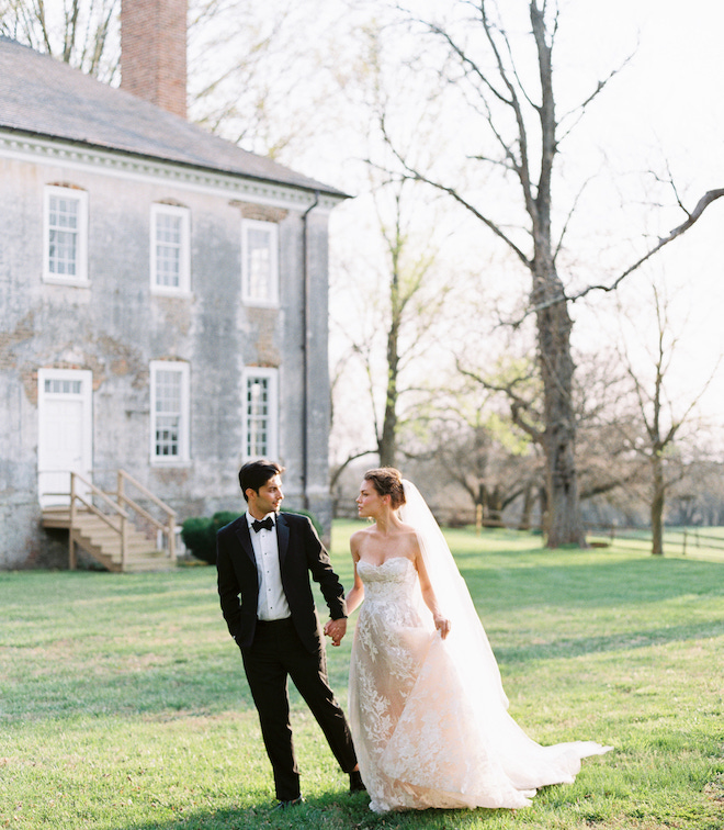 The bride and groom holding hands on the lawn of Salubria.