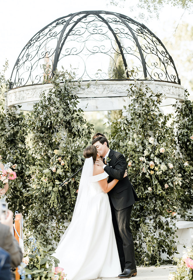 The bride and groom share a kiss at the altar at their alfresco wedding ceremony.