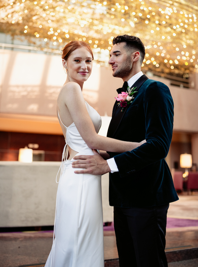 The groom smiling at the bride as she smiles forward in the lobby of the Hilton Houston Post Oak. 