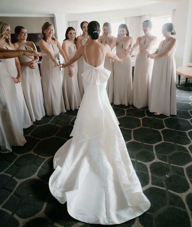 The bride revealing her wedding dress to her bridesmaids. 