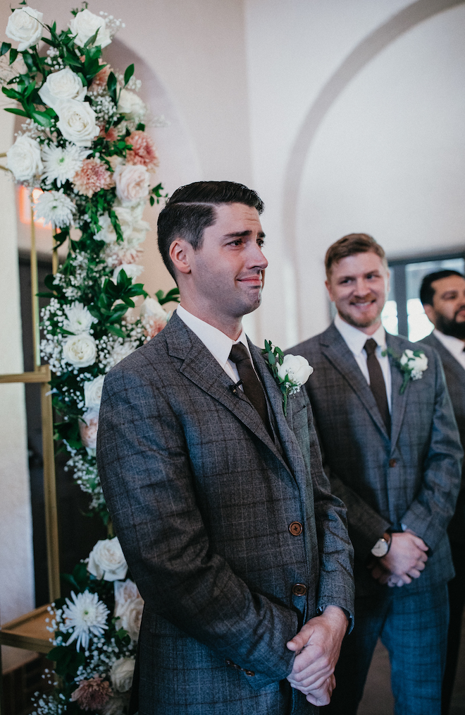 The groom cries at the wedding altar as his bride walks down the aisle. 