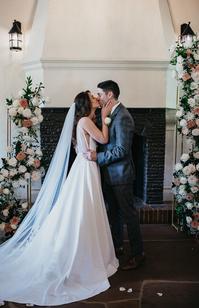 The bride and groom share a kiss at the wedding altar. 