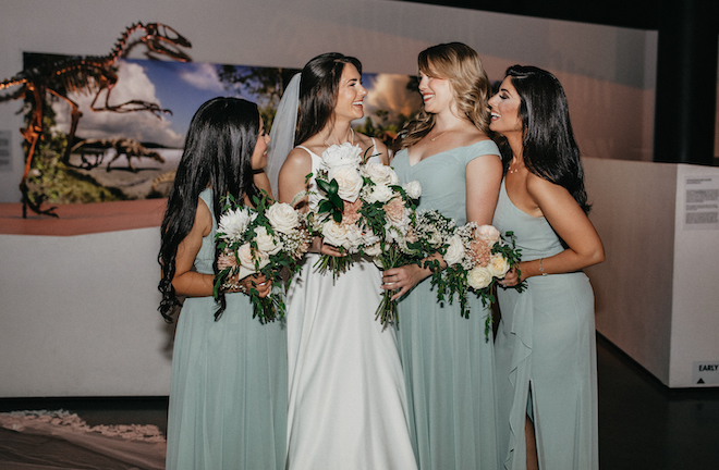 The bride and her bridesmaids share a candid smile at the wedding reception at the Houston museum. 