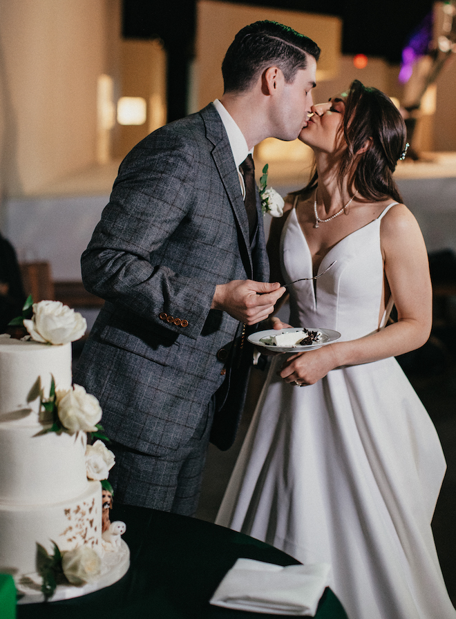 The bride and groom share a kiss after slicing their wedding cake from Cakes by Gina. 