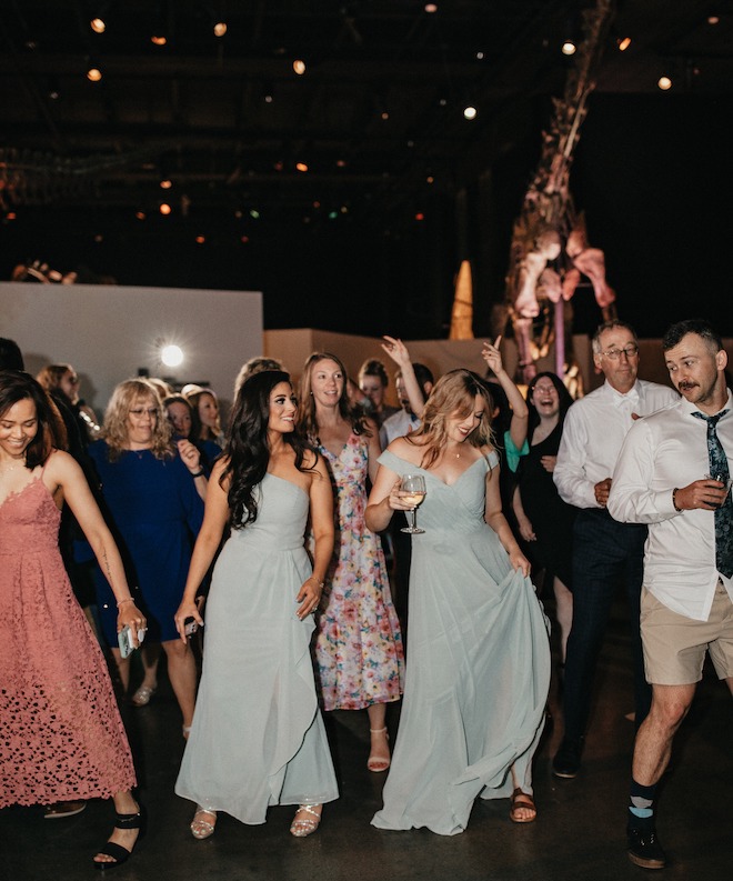 Wedding guests dance on the dance floor under the dinosaur fossils at the Houston museum. 