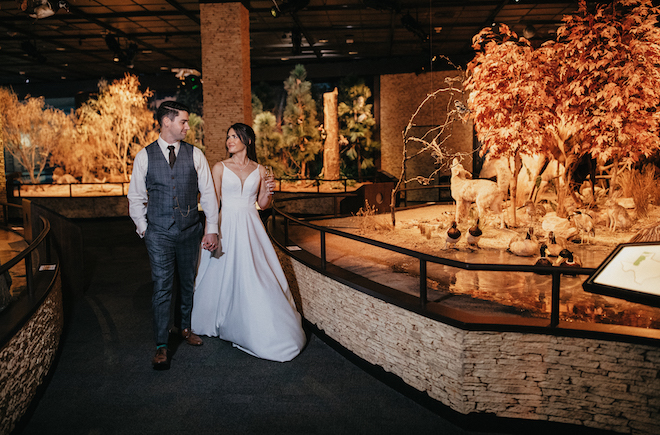 The bride and groom walk around in the Houston Museum while holding hands in one of the exhibits. 