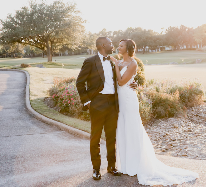 The bride and groom look at each other smiling on the golf course at their wedding venue, the Royal Oaks Country Club.