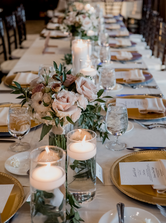 Pink and mauve colored flowers and pillar candles decorate the reception tables. 