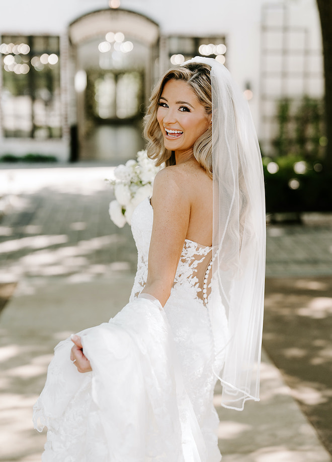 The bride smiling in front of the chapel. 