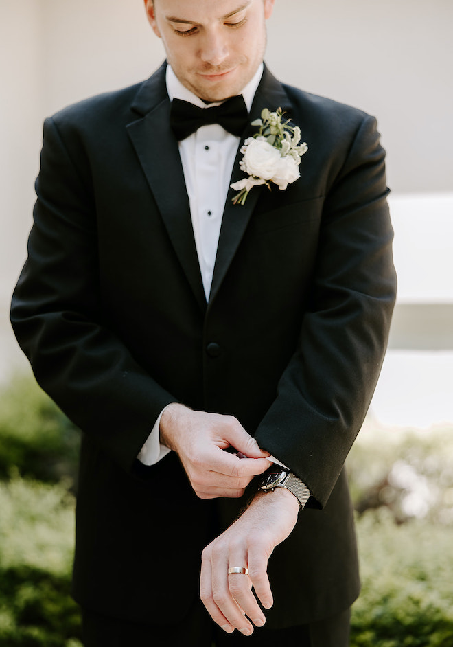 The groom adjusting his sleeve. 