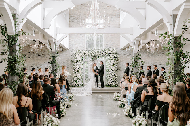 The bride and groom holding hands during their wedding ceremony. 