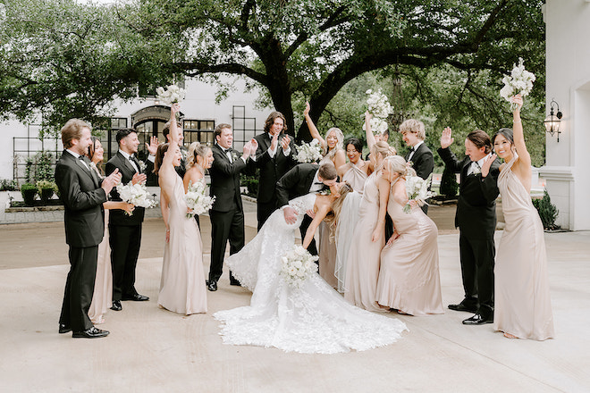 The bride and groom kissing while the wedding party cheers. 