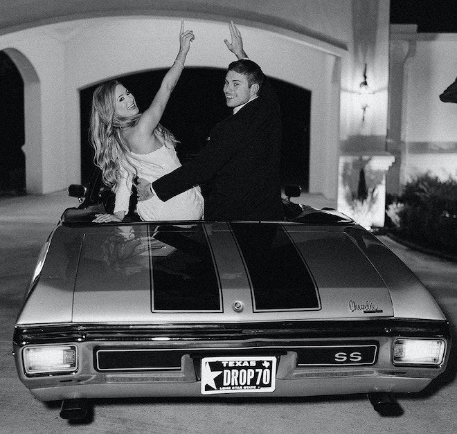 The bride and groom cheering as they leave in a vintage car. 