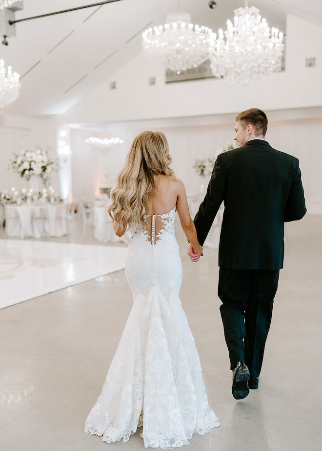 The bride and groom holding hands walking into the reception. 