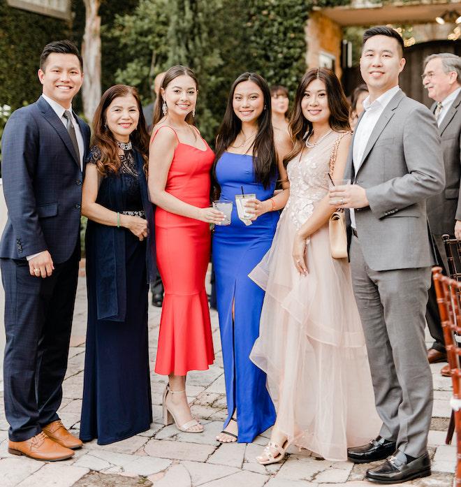 Wedding guests wearing formal gowns and suits. 