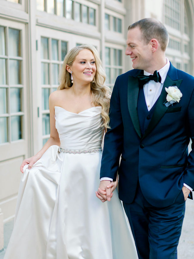 The bride and groom holding hands on the balcony of Crystal Ballroom at the Rice. 