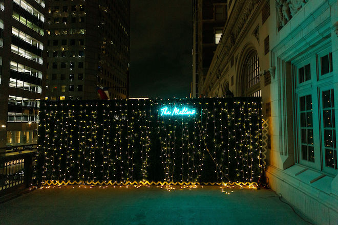 A lit-up sign that says "The Meltons" with the downtown skyline in the background. 