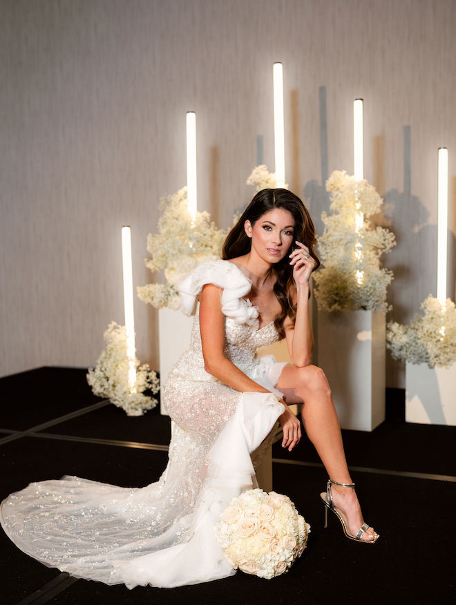 The model poses on the altar next to white flowers for this black and white old Hollywood wedding editorial. 