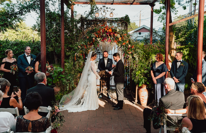 The bride and groom hold hands at the alter at their outdoor wedding ceremony.