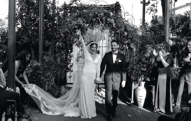 The bride and groom celebrate as they hold hands walking down the aisle as newlyweds.