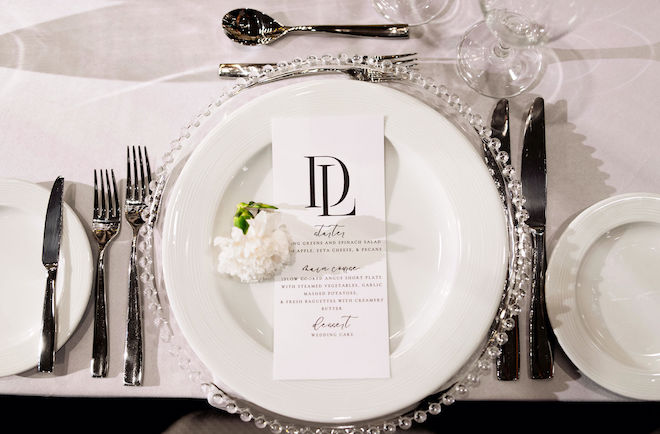 Black and white paper goods are placed on top of the table settings at the reception.