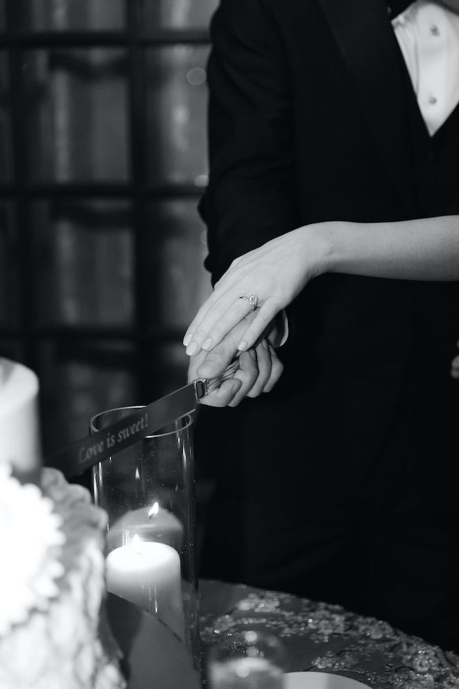 The bride and groom cutting the cake with a knife that says "Love is Sweet!"