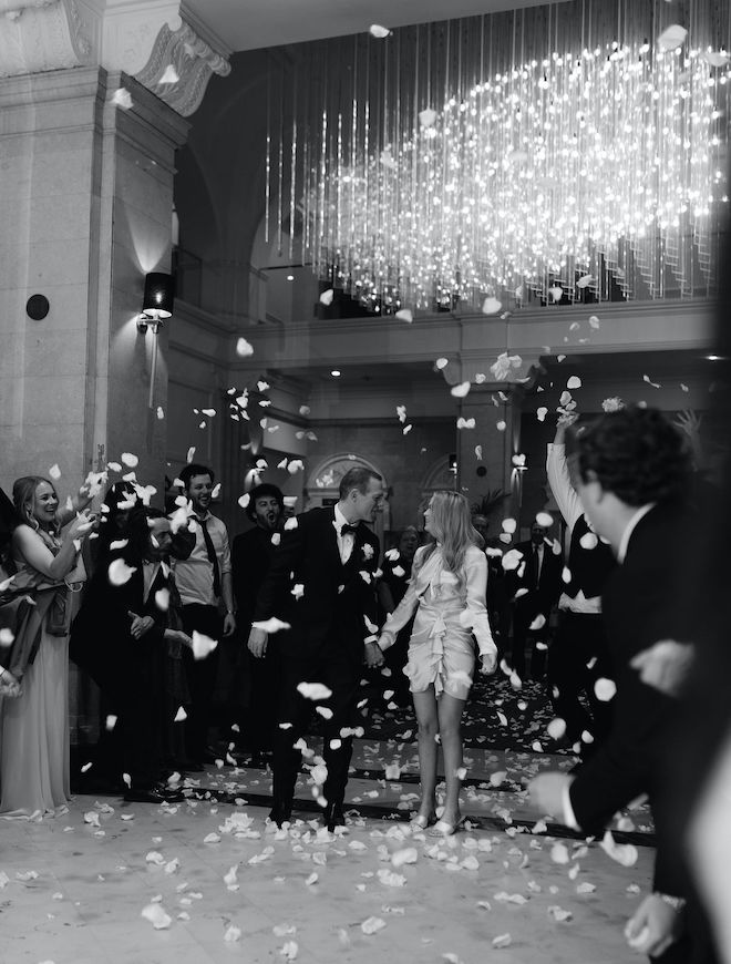 The bride and groom holding hands during their floral petal send off. 