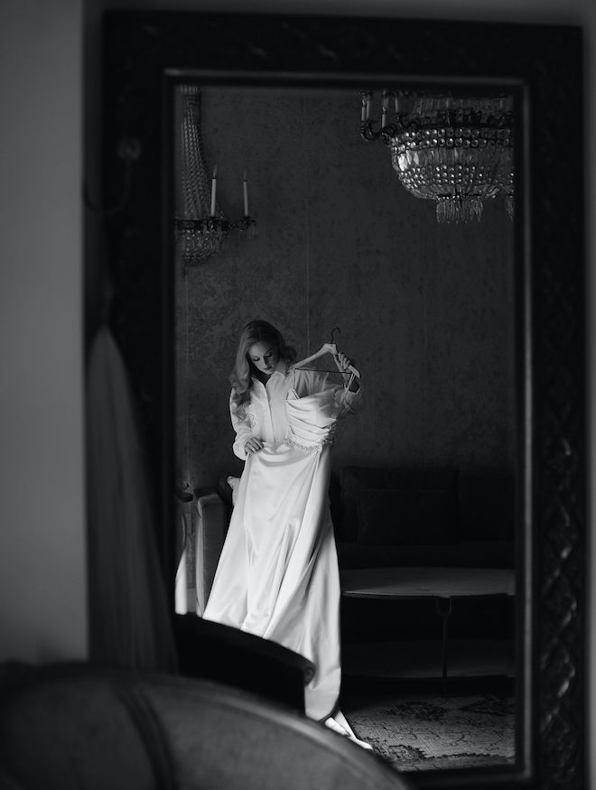 The bride holding her wedding dress on a hanger.