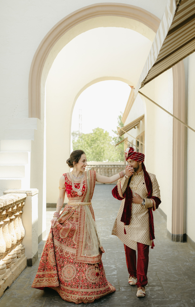 The groom kisses the brides hand as they walk out on the terrace at the wedding venue in Houston, Bell Tower on 34th. 