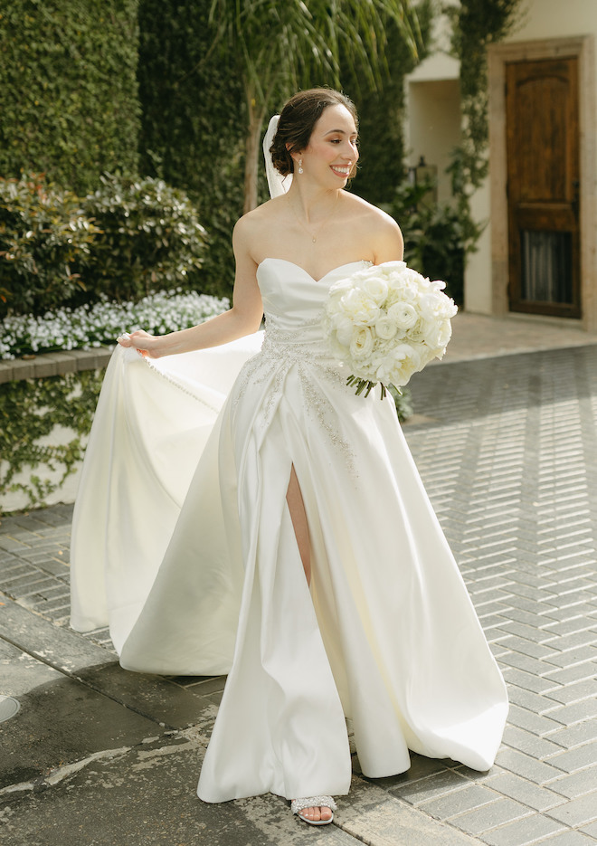 The bride smile and holds her bouquet outside her wedding venue in Houston. 