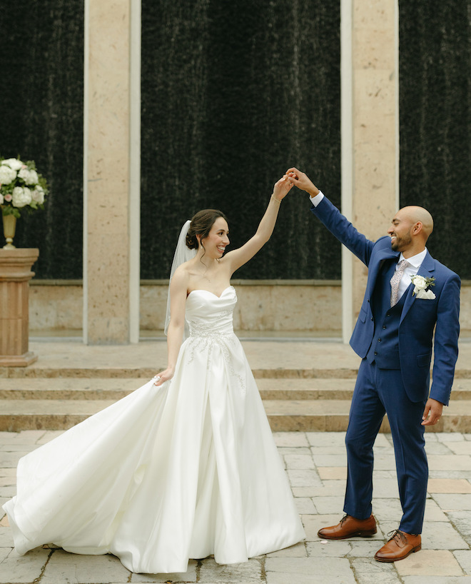 The groom spins the bride outside in front of the Bell Tower on 34th's Waterwall. 