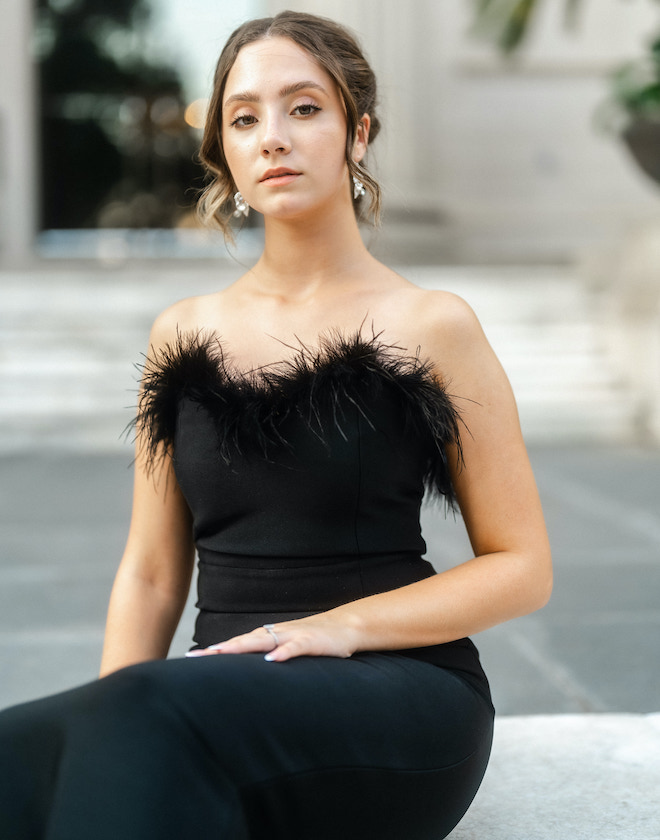 The model wears her hair in a loose updo and is wearing soft-natural makeup. 