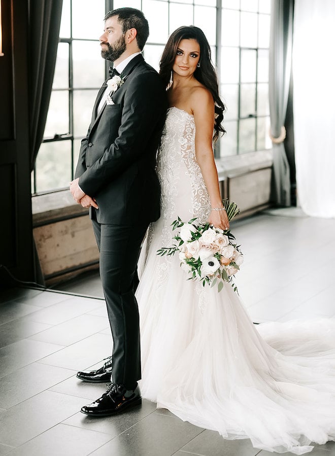 The bride poses behind the groom for their elegant downtown wedding at The Astorian. 