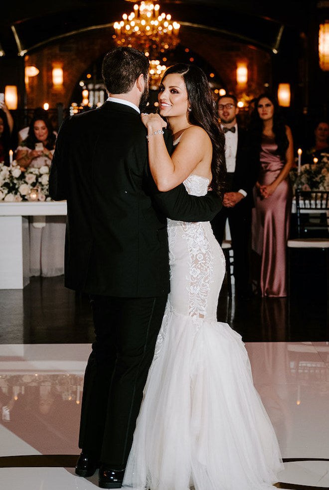 The bride and groom share a dance as friends and family watch from the reception tables. 