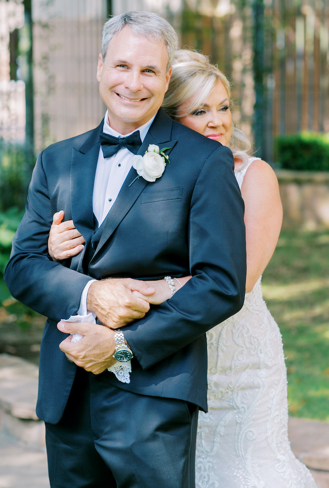 The bride hugs her groom from behind on their wedding day.