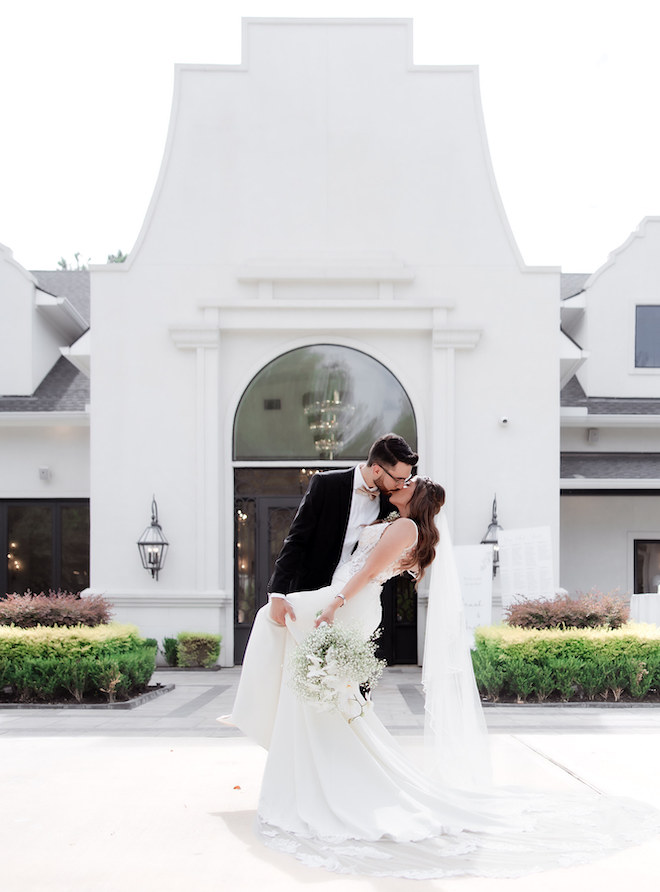 The bride and groom kissing in front of the wedding venue. 