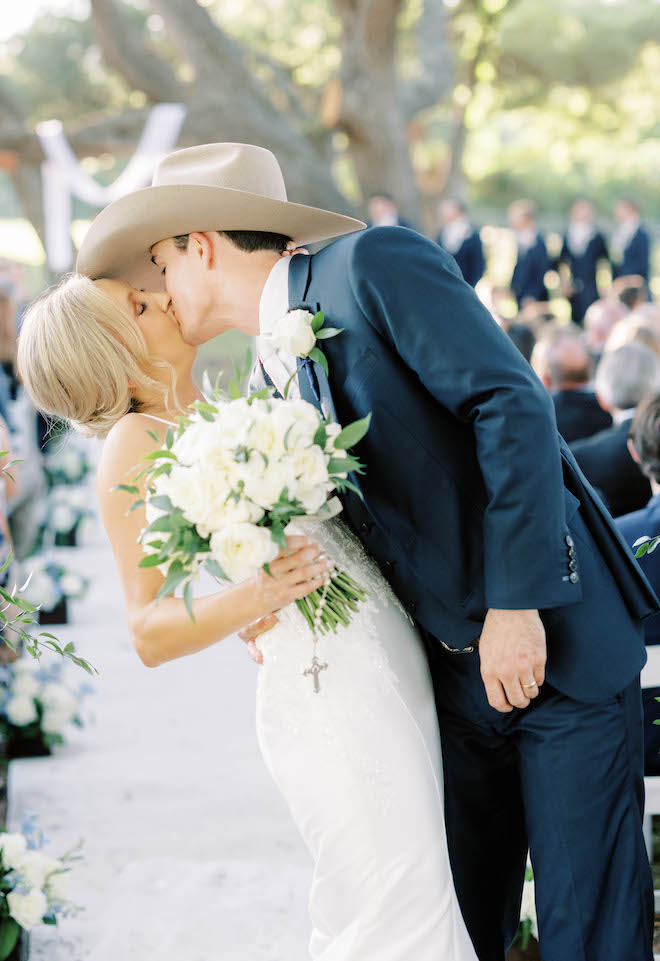 The bride and groom kiss at the end of the aisle after their wedding ceremony.