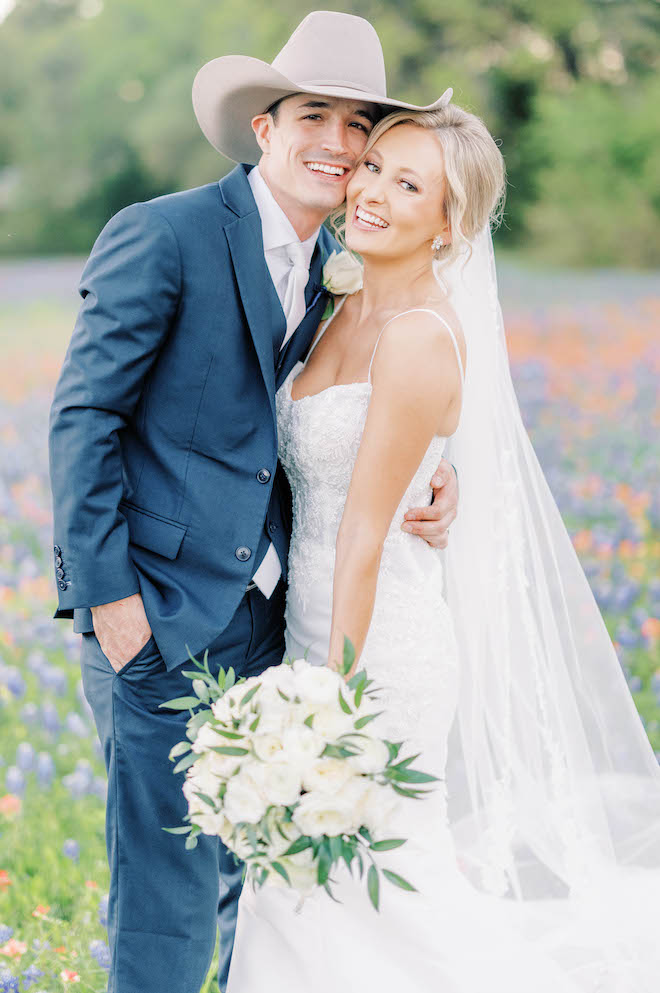 The bride and groom pose in the Texas wildflowers for their sentimental ranch wedding in Brenham, TX.