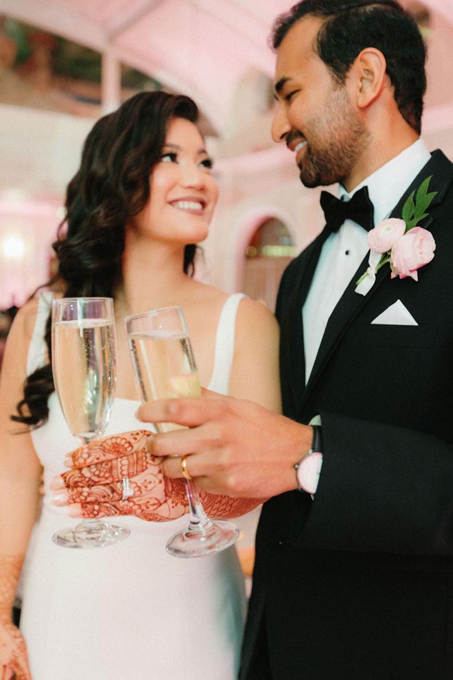 The bride and groom cheers with a glass of Champagne at their ballroom wedding reception.