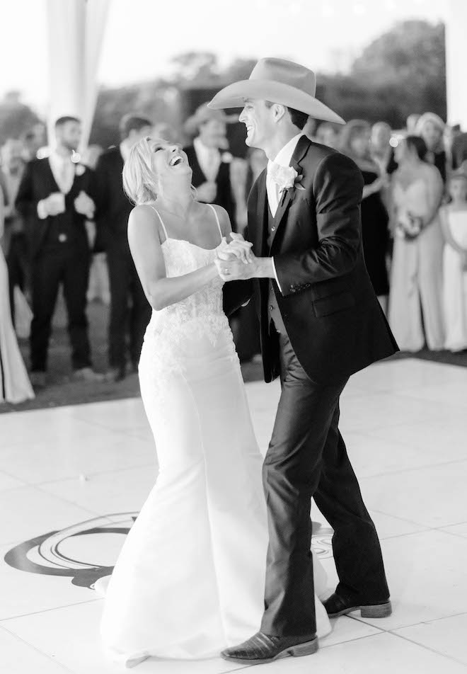 The bride and groom dance at their wedding reception as friends and family gather around to watch.