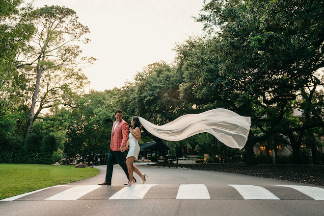 Natalie Hee wearing a white mini dress and veil while crossing the street with her fiance.