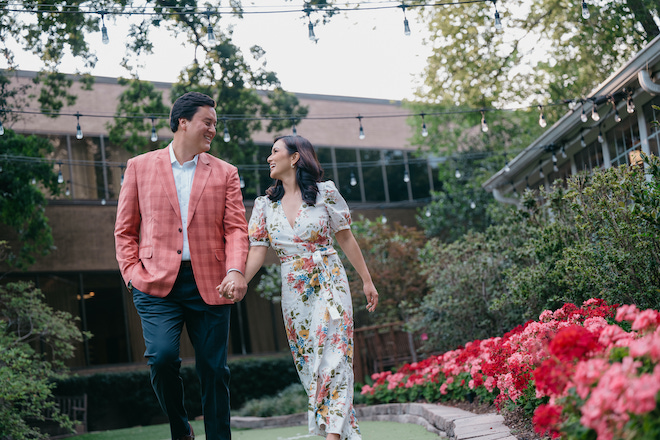 A couple holding hands and smiling at each other while walking. 