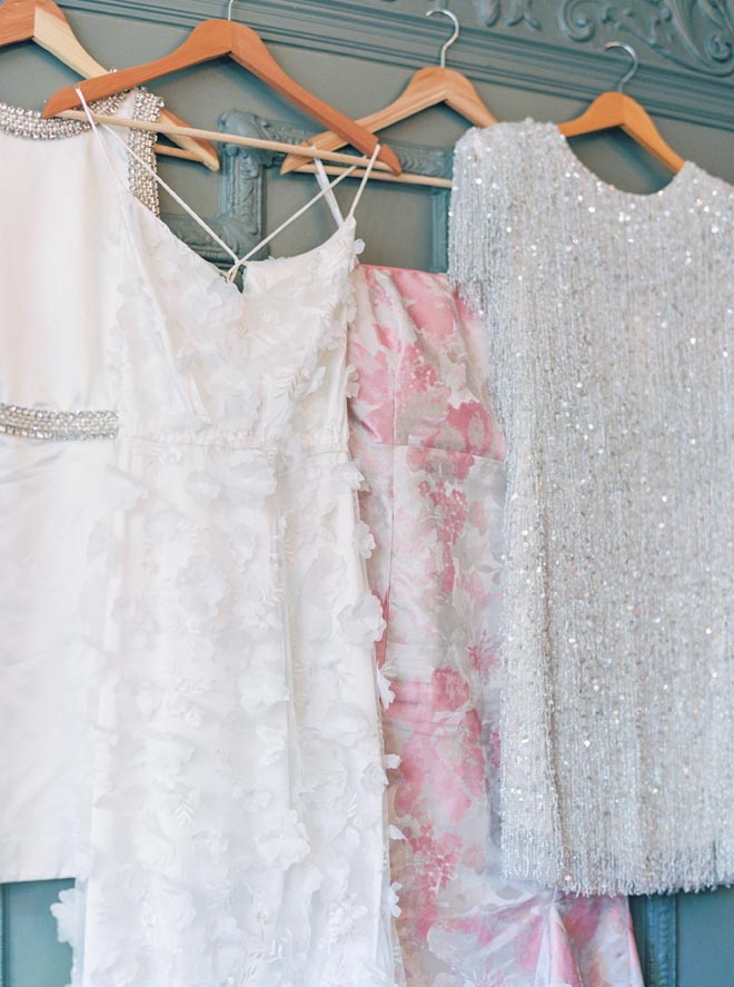 Four dresses hanging against a blue wall. 